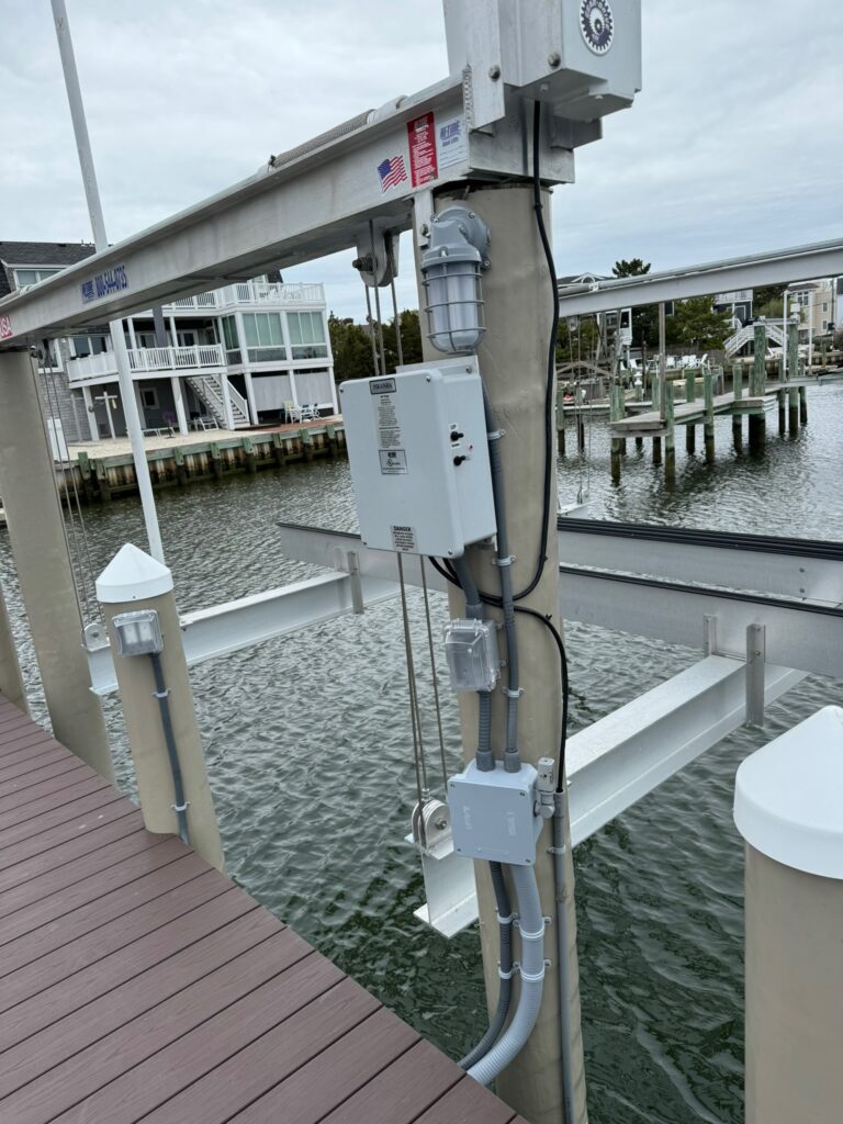 Electric system on a tower with homes and water behind.