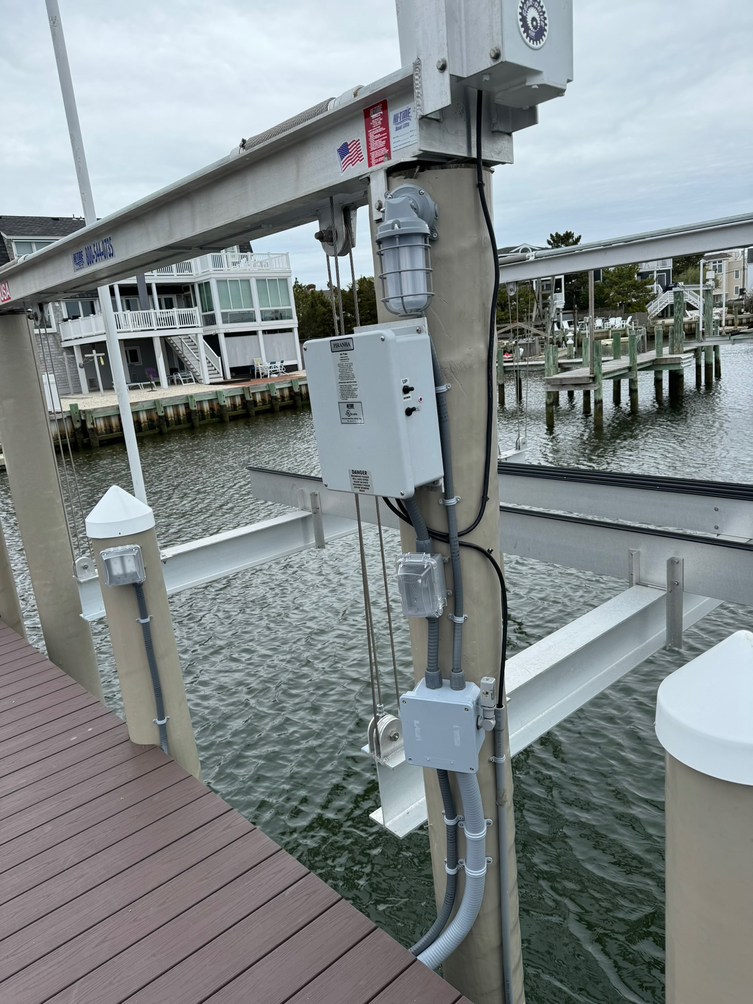 Electric system on a tower with homes and water behind.